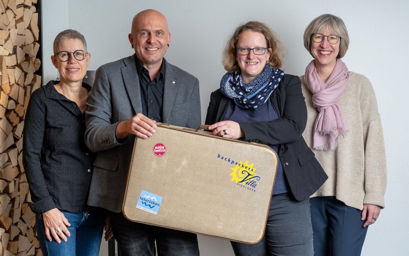Marianne und David Bühler übergeben den an«Backpackers Villa Sonnenhof»-Koffer an die neue Gastgeberin Isabelle Gruner und ihre Stellvertreterin Catherin Quirin (v.l.).