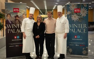 Vier Personen stehen vor zwei Plakaten zur Serie Winter Palace